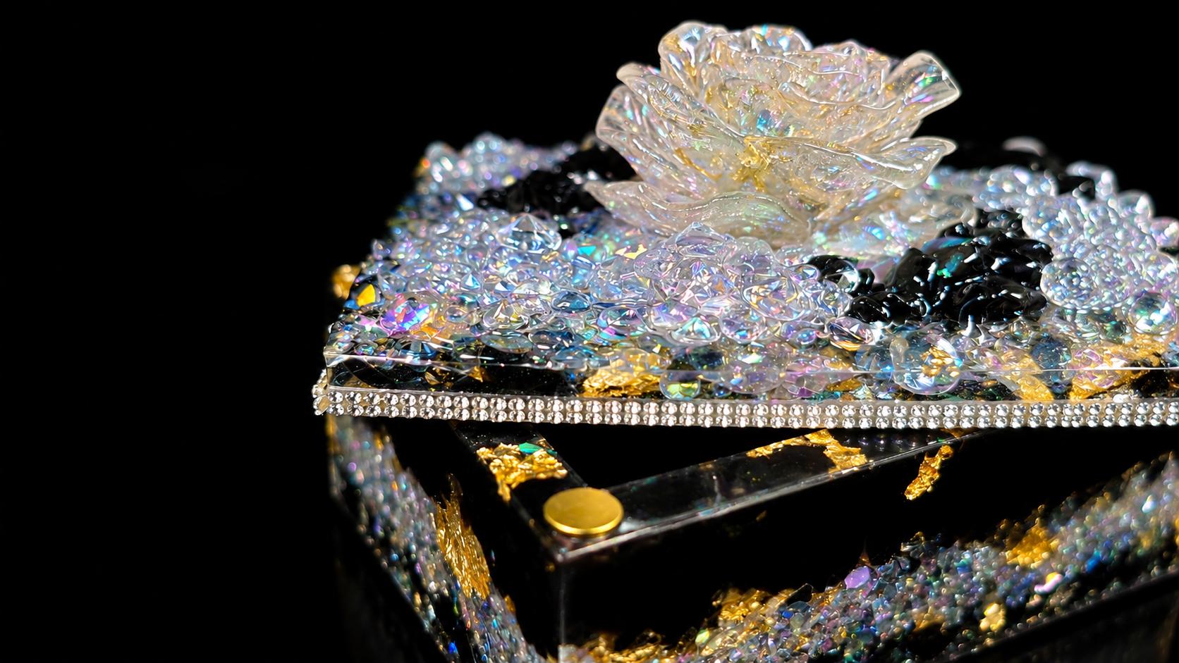 Detail of a sculpted crystal rose set into a resin lid over obsidian.